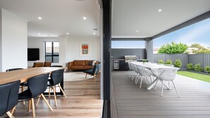 A modern kitchen with a built-in oven and a dining area with a wooden table and chairs. - Rigby Retreat at St Leonards (St Leonards)