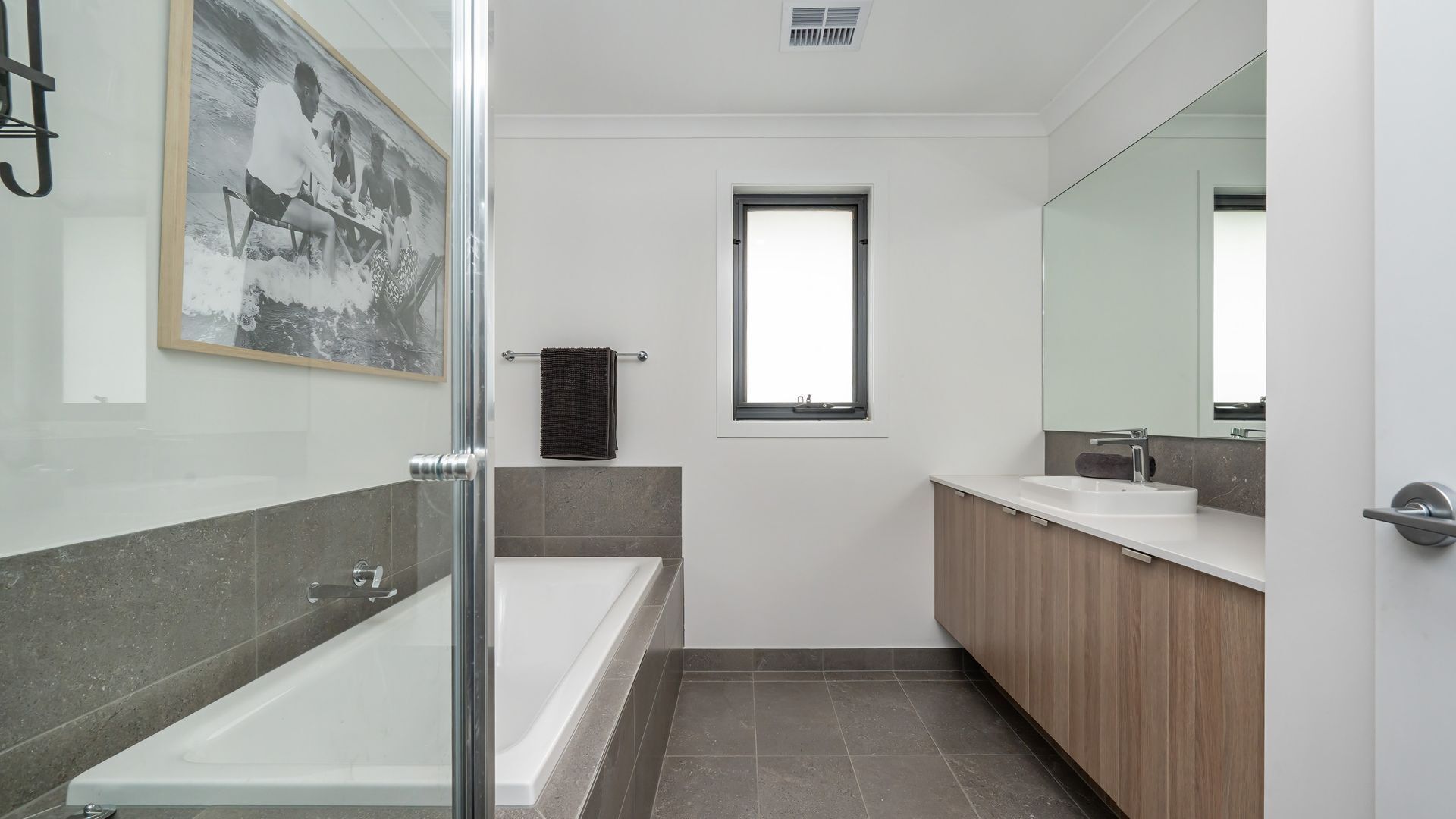 Une salle de bain moderne avec une douche à l’italienne, une baignoire, un grand miroir et une fenêtre.