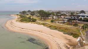 A coastal area with a sandy beach, a park with pathways, and residential buildings in the background. - Rigby Retreat at St Leonards (St Leonards)