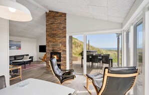 A modern living room with a fireplace, a dining area, and a view of the beach. - Amazing home in Hvide Sande with sauna (Hvide Sande)
