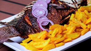 A plate with grilled fish, French fries, and sliced red onions. - Rubax motel mbarara  (Mbarara)