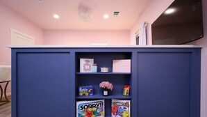 Un comptoir d’accueil avec un meuble bleu, un mur rose et un téléviseur à écran plat fixé au-dessus.