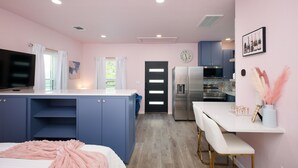 Une chambre compacte comprenant un lit, un téléviseur et un espace bureau.
