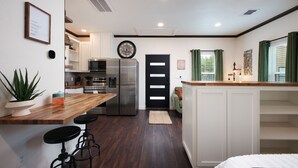 A modern kitchen with a wooden countertop, stainless steel appliances, and a black door.