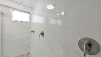 Un baño moderno con ducha, ventana y suelo de mármol.