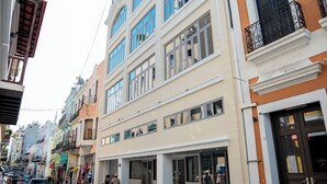A street with buildings, a cobblestone road, and a few pedestrians. - Hotel Milano (San Juan)