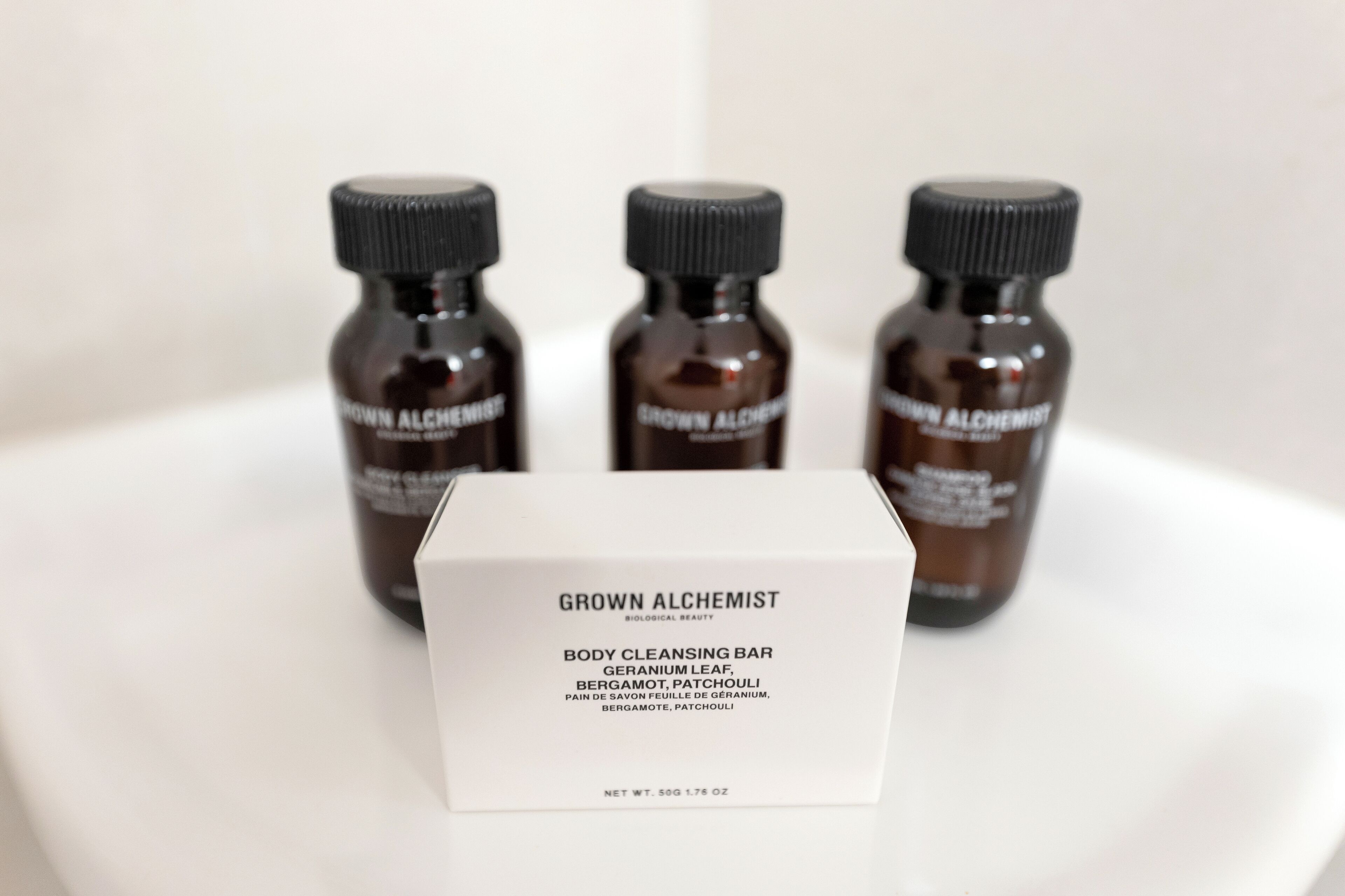A product box labeled 'GROWN ALCHEMIST' with three bottles of body cleansing bar in the background.