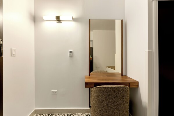 A small room with a wooden desk, a chair, a wall-mounted light, and a mirror. - Hotel Milano (San Juan)