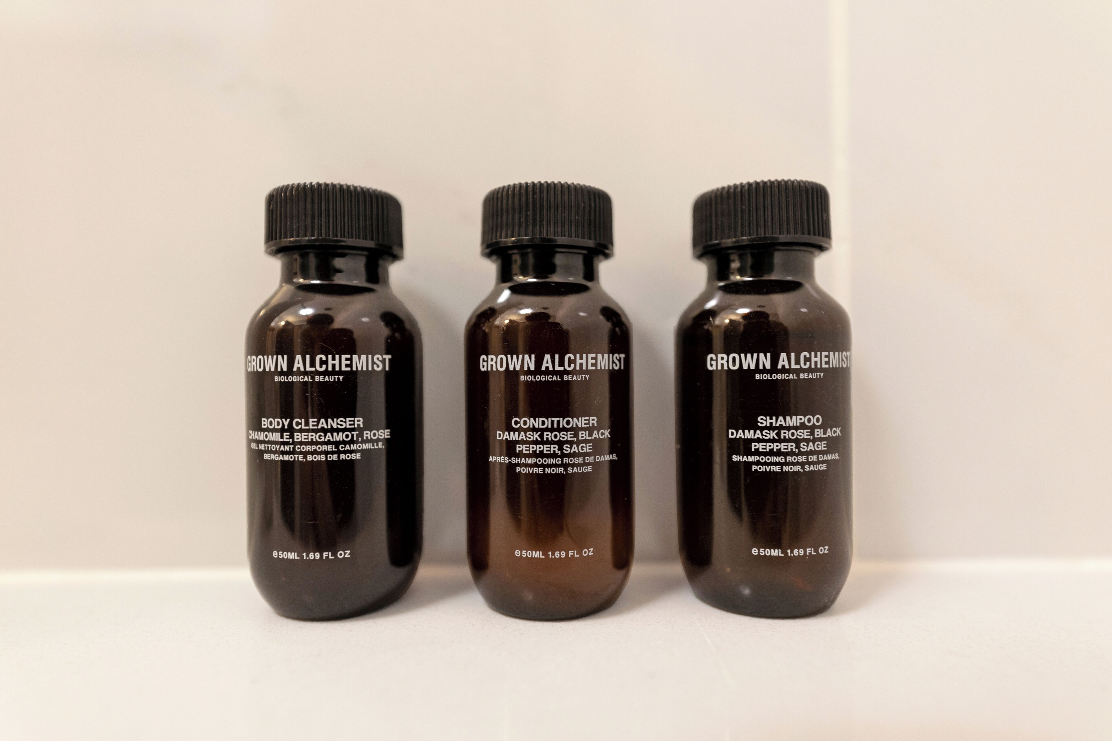 Three bottles of 'Grown Alchemist' products: body cleanser, conditioner, and shampoo.