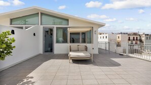 A modern apartment with a balcony, a swing chair, and a view of the cityscape. - Hotel Milano (San Juan)