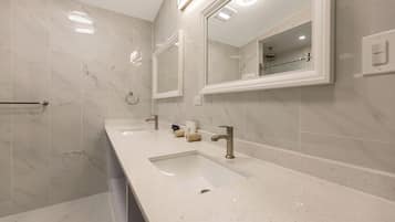 Une salle de bain moderne avec deux lavabos, un grand miroir et un espace douche.