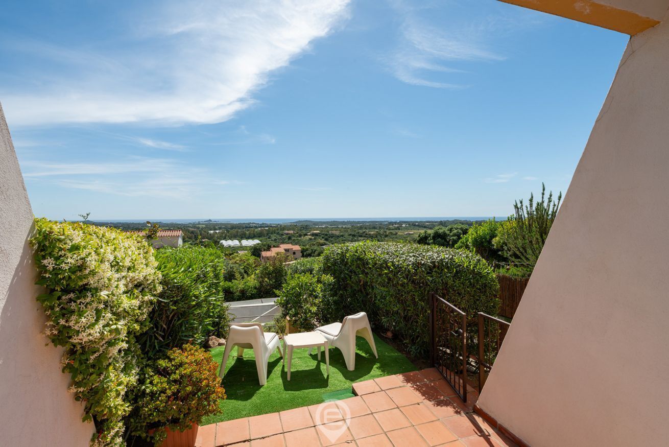 A balcony with a view of the countryside, a small table, and two chairs.