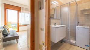 Un bagno moderno con doccia, lavabo e wc. Si nota un telaio di legno e una finestra con tende.