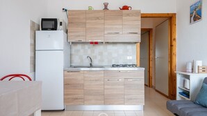 Angolo cottura compatto con microonde, frigorifero e fornello a gas.