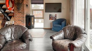 A living room with leather sofas, a fireplace, a TV, and a large window. - 3 bedroom gorgeous home in Hesselager (Hesselager)