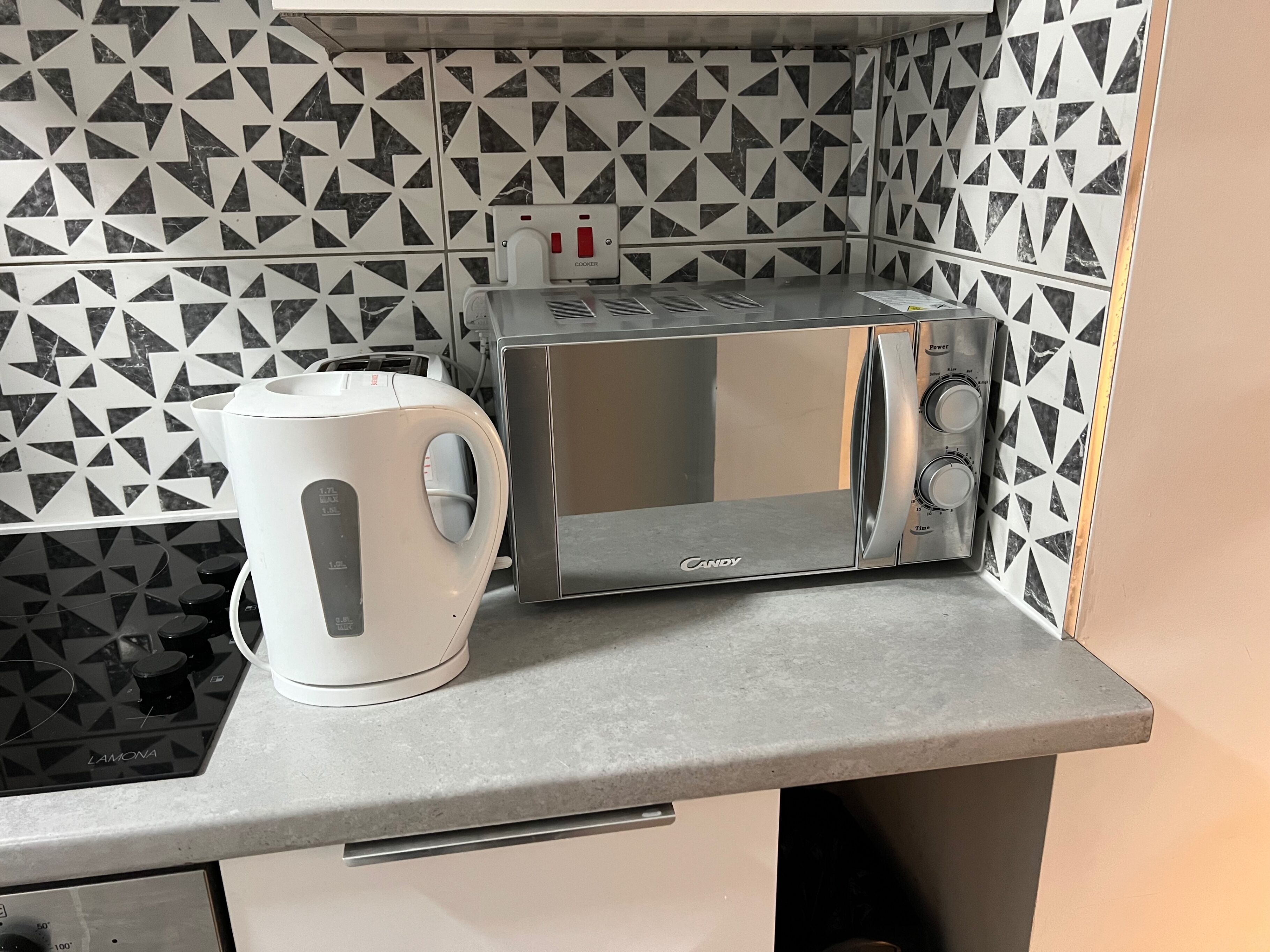 A kitchen with a toaster, a kettle, and a microwave on a countertop.