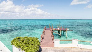 A wooden pier leading to a wooden deck with lounge chairs over turquoise water. - Exclusive Ocean Villa in Nassau (Nassau)