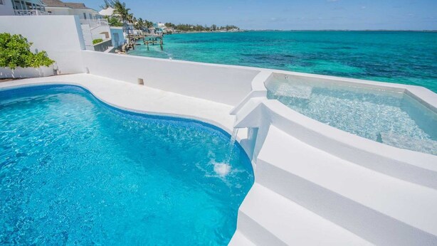 A swimming pool with clear blue water, a hot tub, and a view of the ocean. - Exclusive Ocean Villa in Nassau (Nassau)