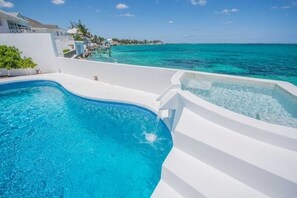 Una piscina con agua azul cristalina, un jacuzzi y vista al océano.