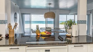 A kitchen with a large island, a hanging light, and a view of the ocean. - Exclusive Ocean Villa in Nassau (Nassau)
