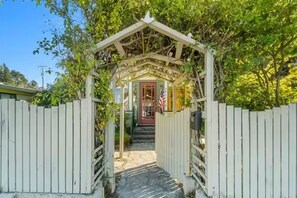 A wooden archway leading to a building with a red door and an American flag.