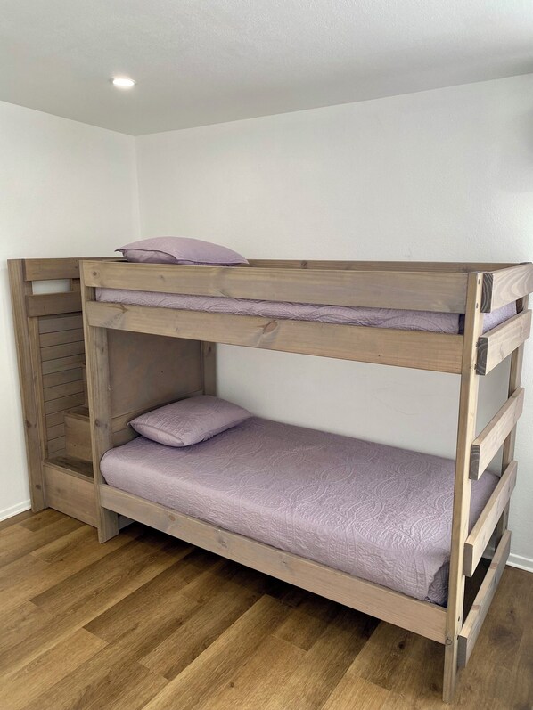 A bunk bed with a wooden frame and a purple mattress.