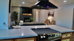 A modern kitchen with a central island, built-in oven, and a black range hood.