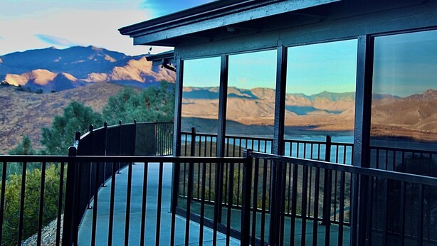 A balcony with a view of mountains and a lake.