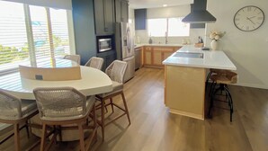 A modern kitchen with a dining area, wooden flooring, and a large window.