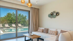 Een moderne woonkamer met een witte bank, een houten salontafel en een glazen deur naar een zwembad.
