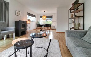 A modern living room with a grey sofa, a round coffee table, a dining area with a table and chairs, and a fireplace. - 2 bedroom nice home in Oostkapelle (Oostkapelle)