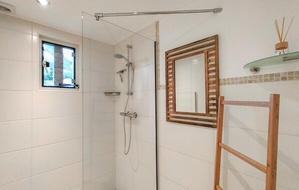 A shower with a glass door, a small window, and a wooden-framed mirror. - 2 bedroom nice home in Oostkapelle (Oostkapelle)