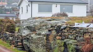 Valkoinen rakennus, jossa on kaksi suurta ikkunaa, edessä kivimuuri ja rakennukseen johtava polku.