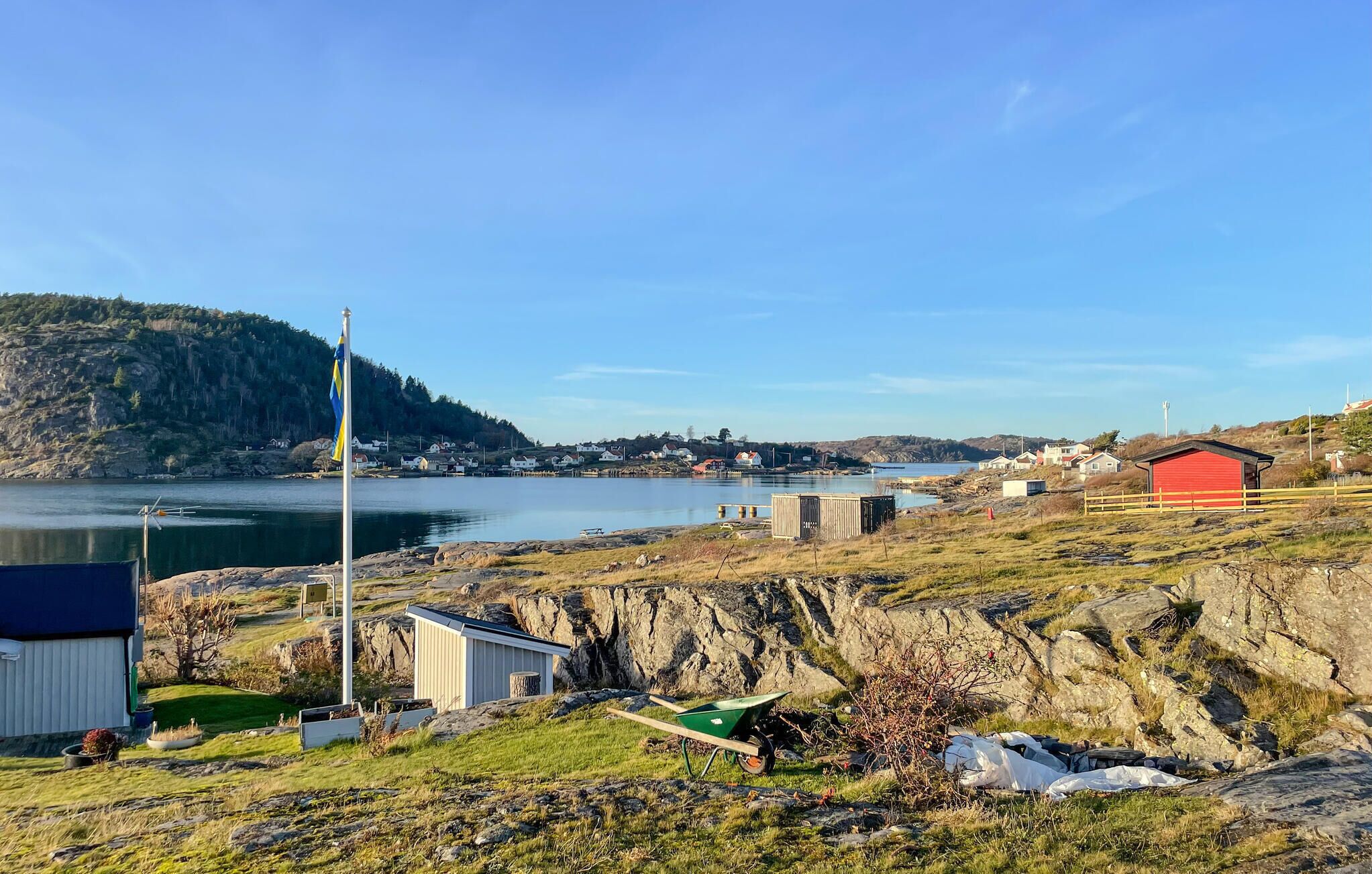 A coastal village with houses, a red shed, and a flagpole.