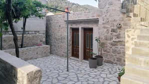 A stone courtyard with a wooden door, potted plants, and a pergola. - Awesome apartment in Hvar with WiFi (Hvar)