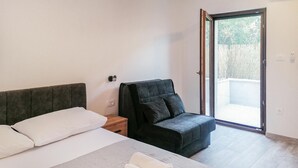 A hotel room with a bed, a chair, a small table, and a sliding glass door leading to an outdoor area. - Awesome apartment in Hvar with WiFi (Hvar)