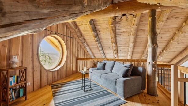 A cozy attic room with a wooden ceiling, a round mirror, a gray sofa, and a striped rug. - Awesome home in Waffenbrunn with sauna (Waffenbrunn)