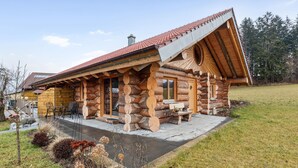 A log cabin with a sloped roof, a chimney, and a porch with a table and chairs. - Awesome home in Waffenbrunn with sauna (Waffenbrunn)