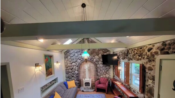 Un salon chaleureux avec un mur en pierre, une cheminée, un canapé et un téléviseur.