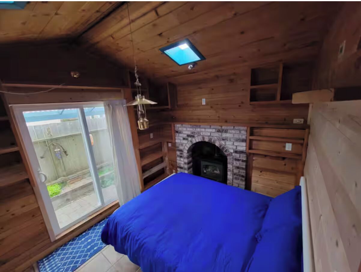 Ein Zimmer in einer Holzhütte mit einem Bett, einem Kamin und einem Fernseher.