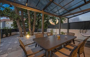 A covered outdoor patio with a rectangular table and chairs, surrounded by trees and a view of the neighborhood. - Stunning home in Vodice with sauna (Vodice)