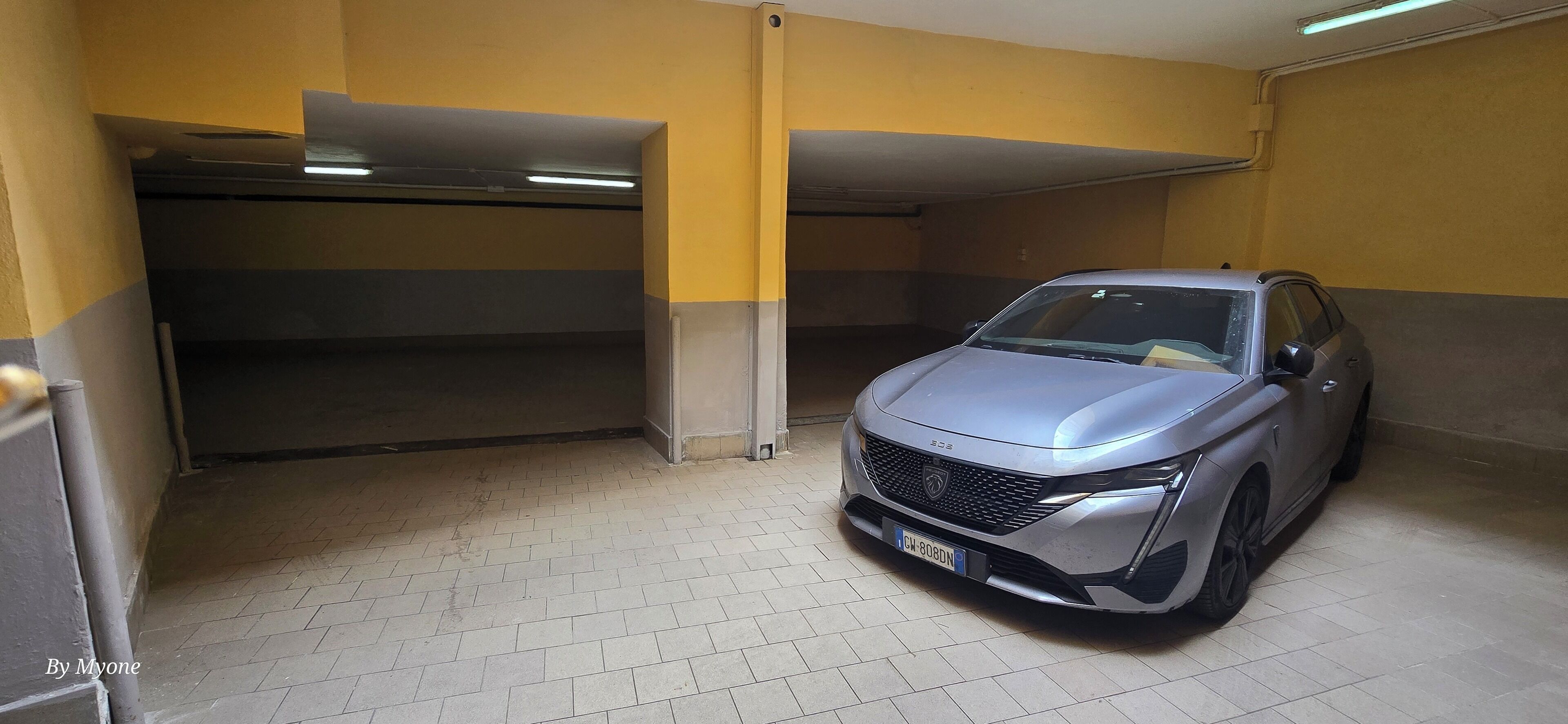Un parking où une voiture argentée est garée dans une place.