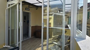 A balcony with a glass door leading to an interior space, wooden flooring, and a view of adjacent buildings. - La Dimora Di Parthenope (Naples)