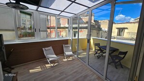 A sunlit balcony with two white chairs, a table, and a view of the cityscape. - La Dimora Di Parthenope (Naples)