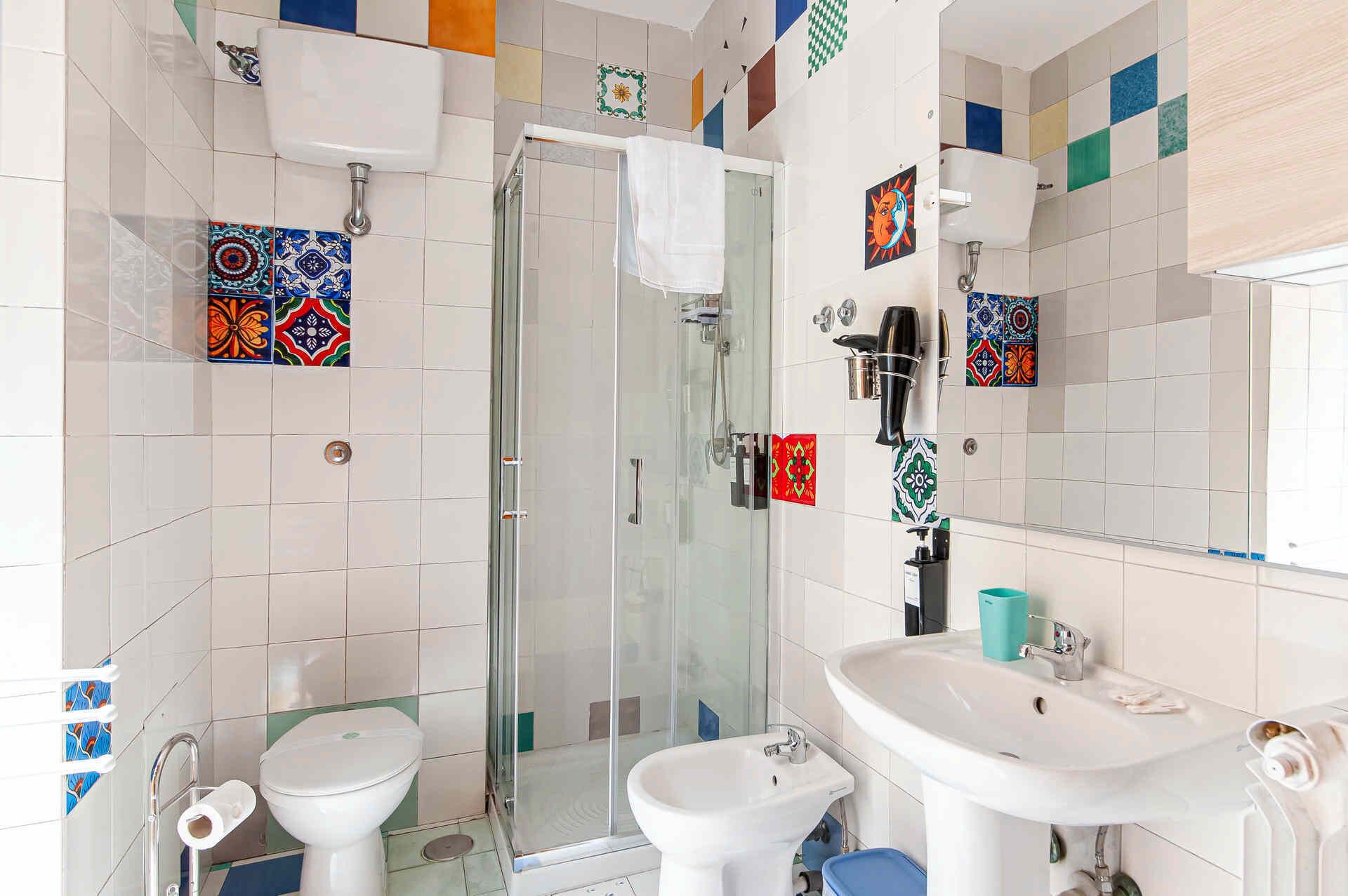A bathroom with a glass-enclosed shower, two sinks, and a toilet.