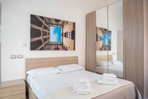 Habitación de hotel con una cama, un espejo grande y una pintura de un edificio.