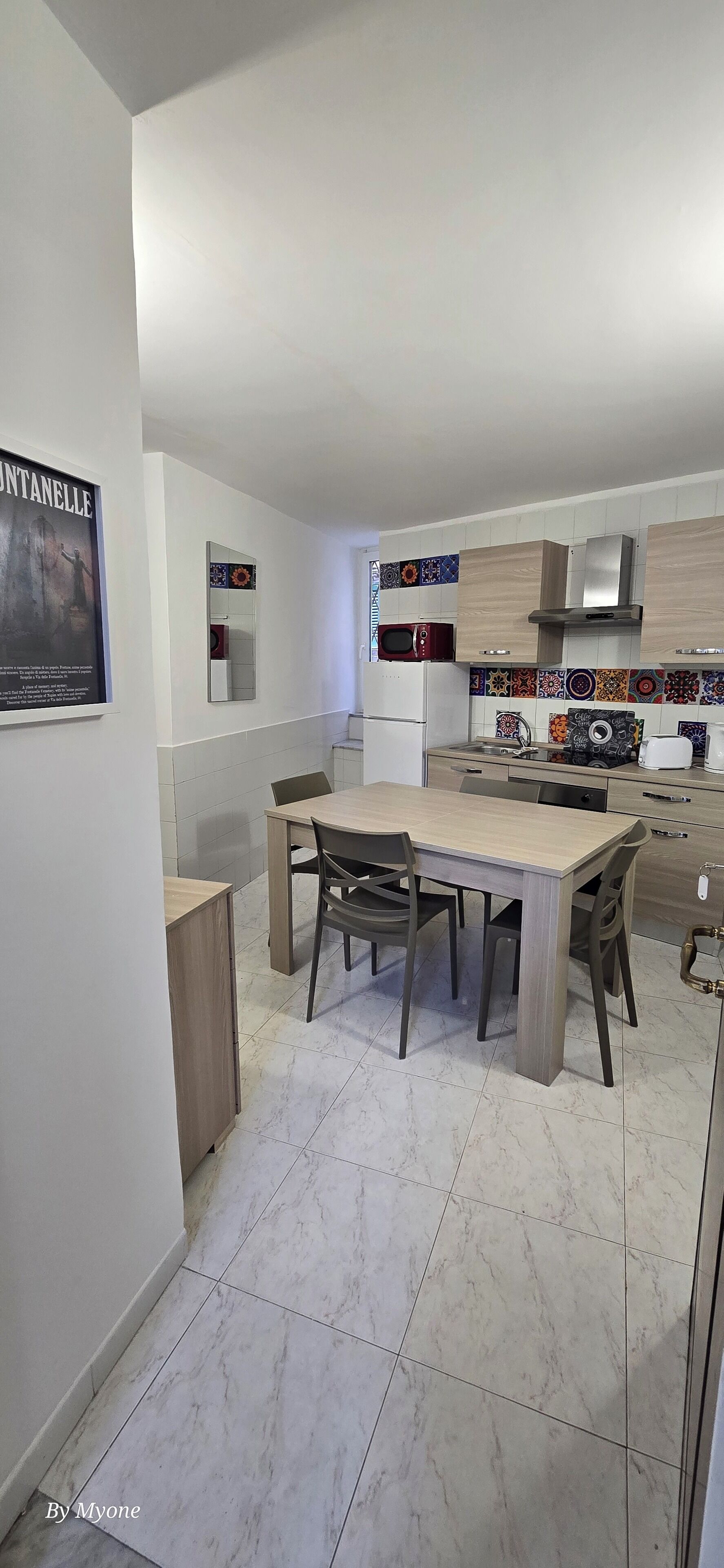 A modern kitchen with a dining area, featuring a marble floor, wooden cabinets, and a microwave.