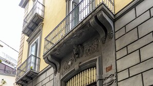 A building with a large wooden door, a balcony with metal railings, and a blue sign indicating a medical facility. - La Dimora Di Parthenope (Naples)