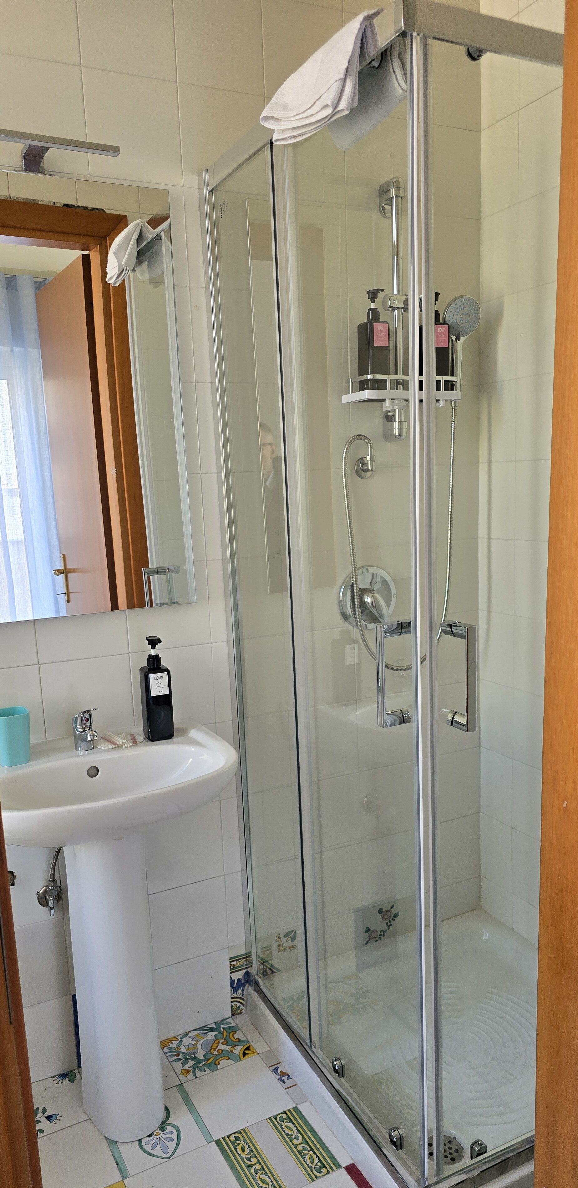 Une salle de bain avec une douche à parois de verre, un lavabo blanc et un miroir.