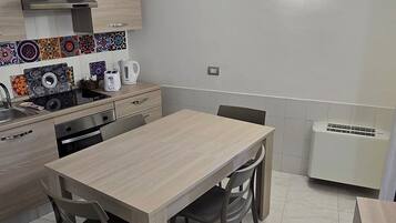 Una cocina moderna con una mesa de madera, sillas, estufa y microondas.
